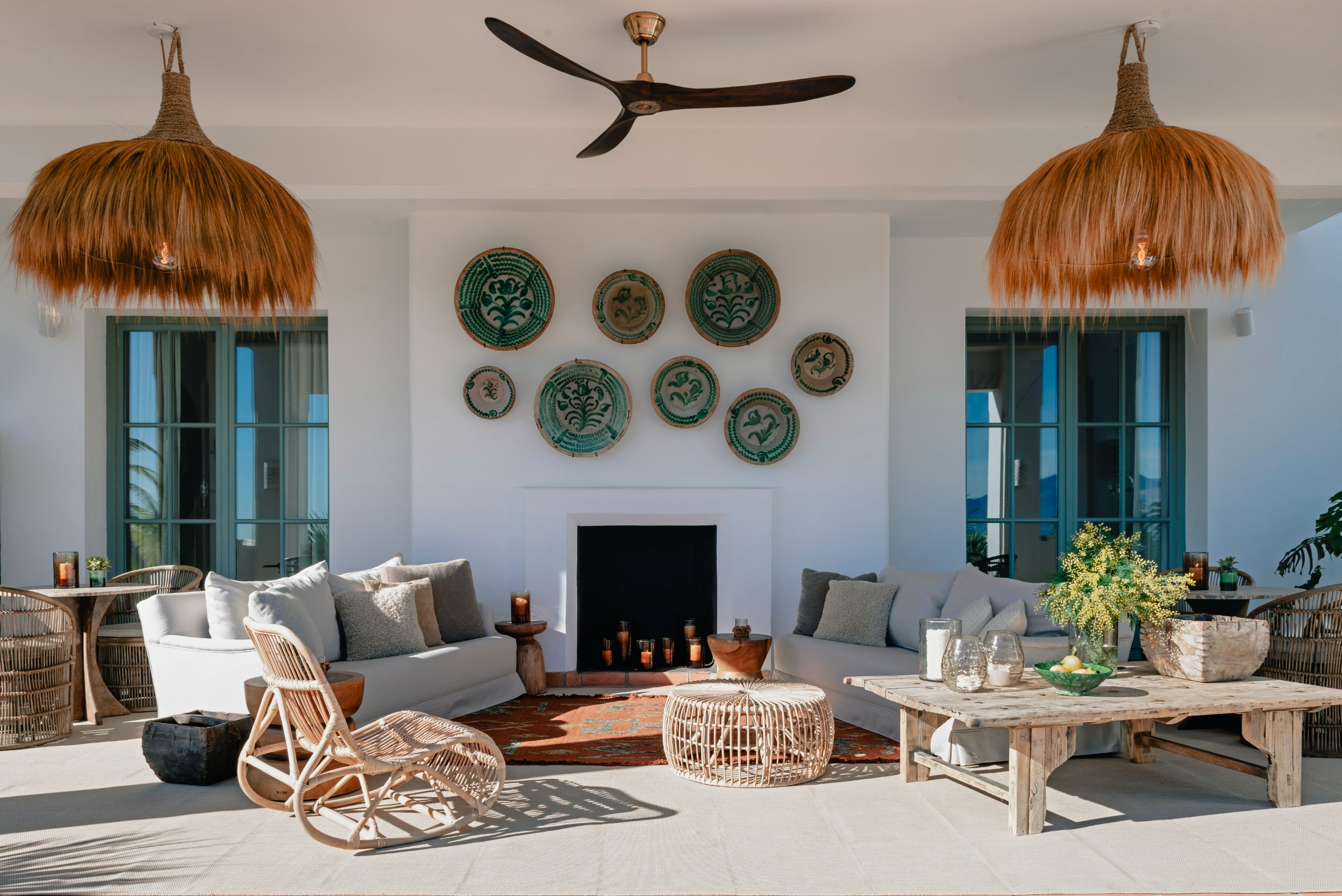 Outdoor lounge with fireplace, ceramic wall art, woven pendants